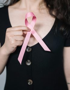 A woman holds a pink ribbon symbolizing breast cancer awareness, promoting health advocacy.