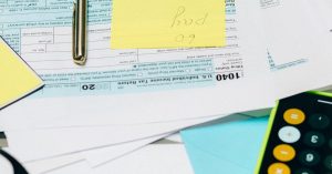 Close-up of tax documents with a calculator, pen, and notes, ideal for financial content.